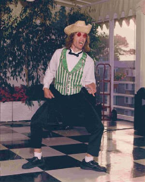 Paul in a straw hat and vest doing a fun, high-energy dance move