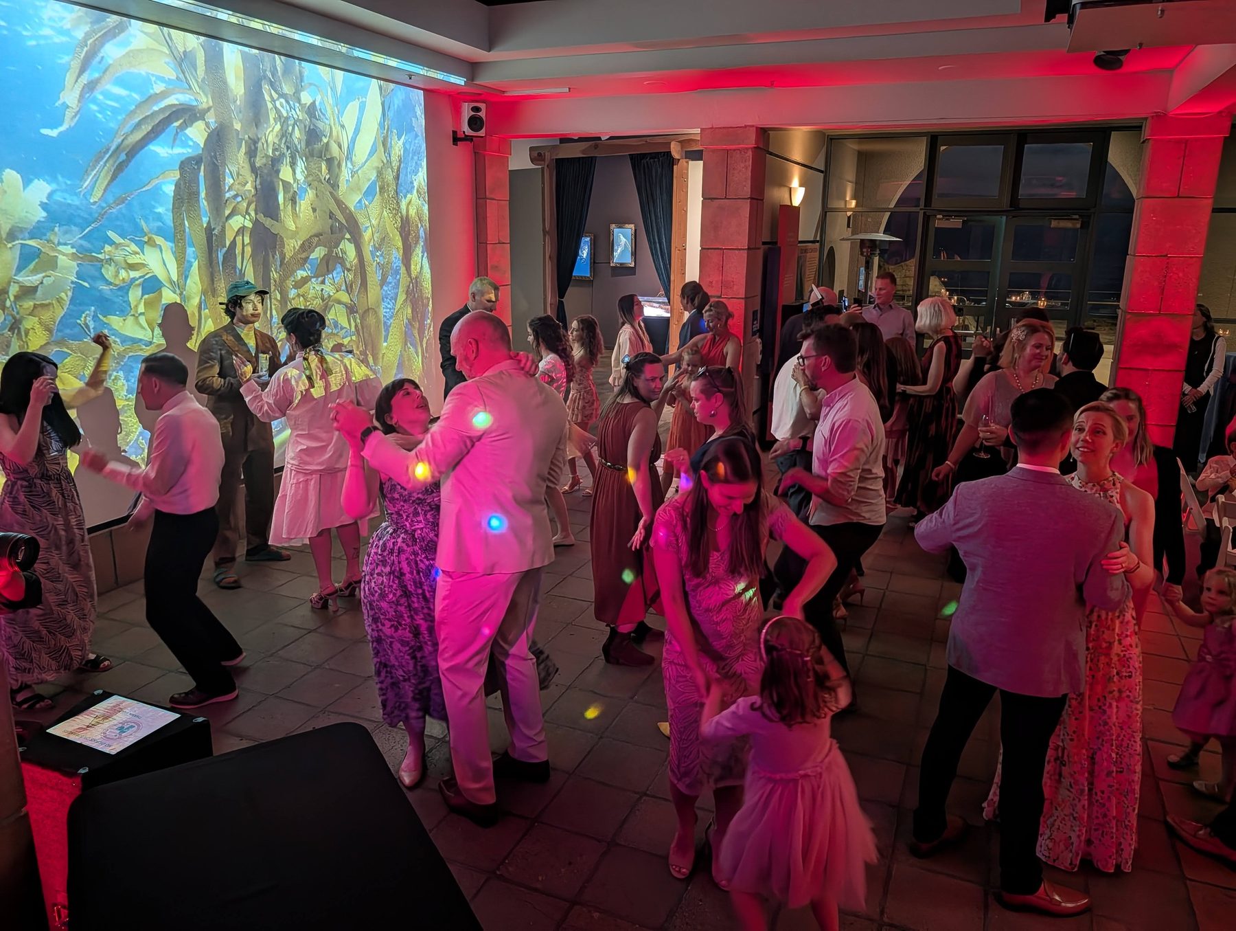 Guests packing the dance floor under colorful lights at a Birch Aquarium wedding reception in La Jolla with DJ Paul Peterson