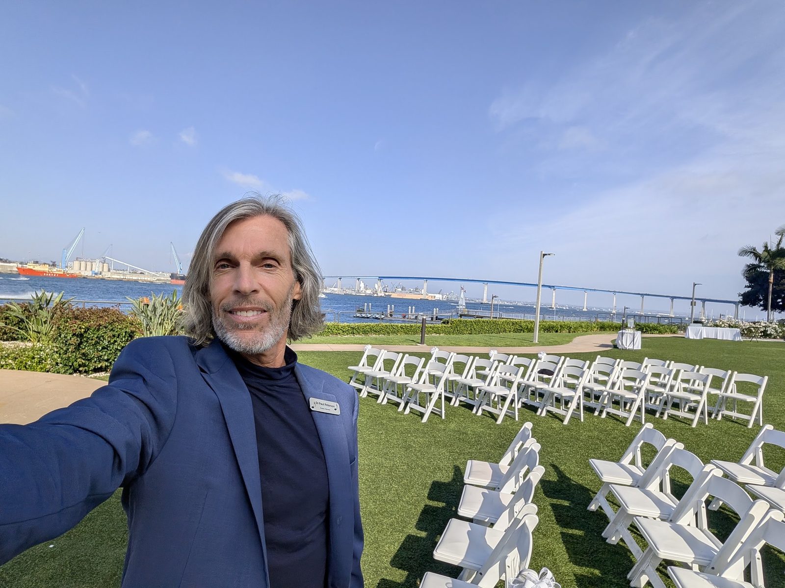 Paul Peterson smiling at an outdoor bayfront wedding ceremony setup at the Coronado Marriott
